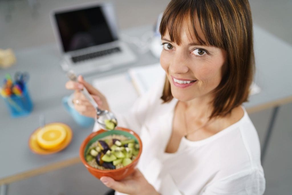 vrouw met bakje fruit op het werk